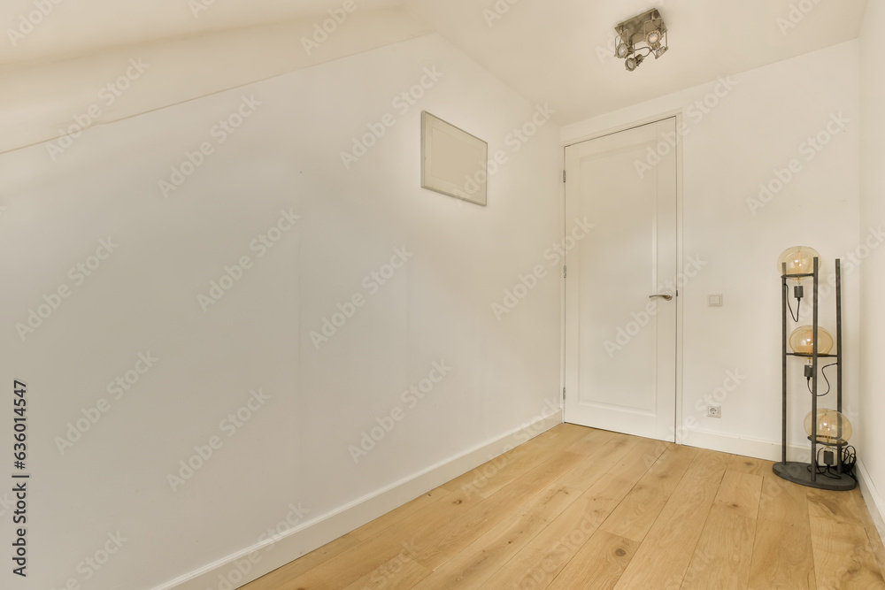 an empty room with white walls and wood flooring on the right side, there is a lamp in the corner an empty room with white walls and wood flooring on the right side, there is a lamp in the corner