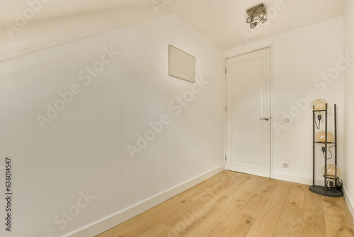 an empty room with white walls and wood flooring on the right side  there is a lamp in the corner