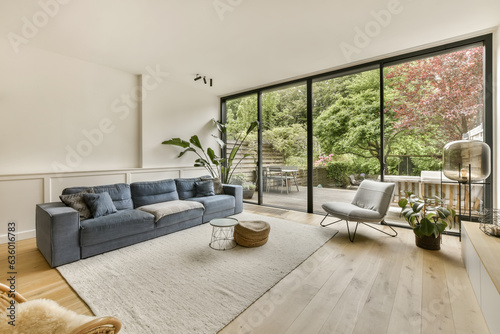 a living room with wood flooring and large windows looking out onto the trees in the backyard area is bright photo