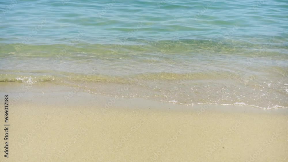 Sea waves hitting the sand on the beach on a sunny day Sea waves hitting the sand on the beach on a sunny day
