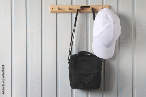 camera bag and a baseball cap on a wooden hanger.