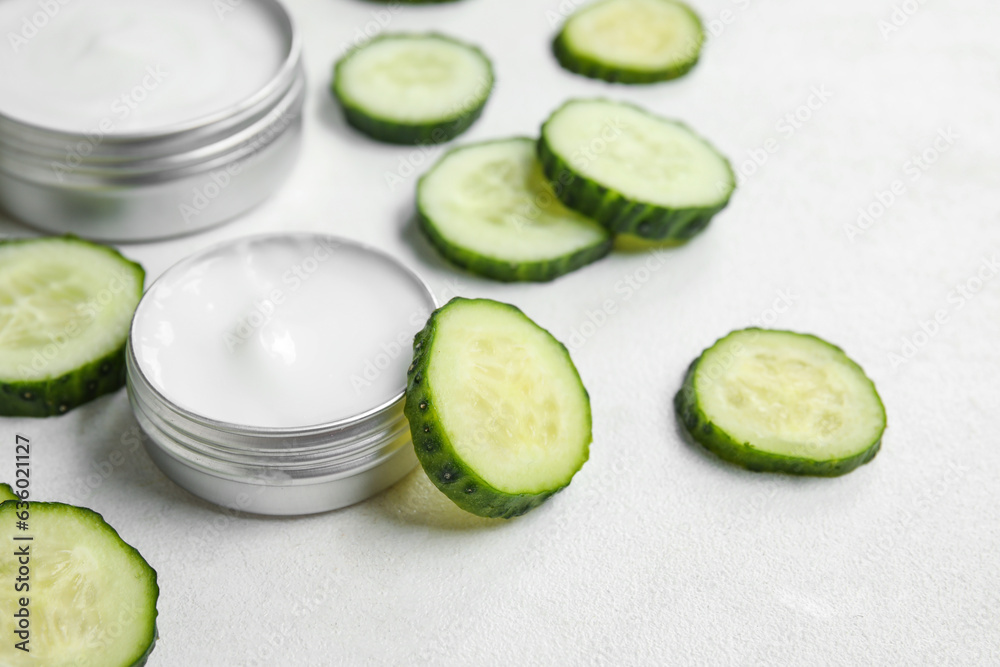 Jars of natural cream and cucumber slices on light background, closeup Jars of natural cream and cucumber slices on light background, closeup