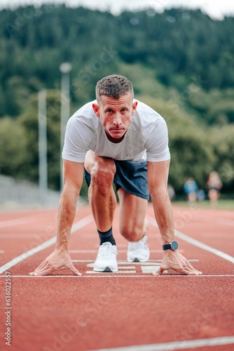 Fit, active man stands on a marked start line, ready to begin a workout