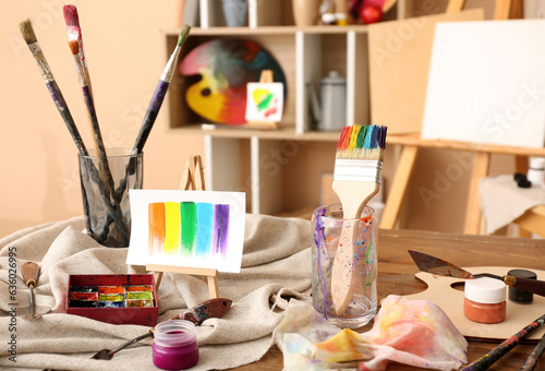 Glass with brushes, paints and mini easel in artist's studio