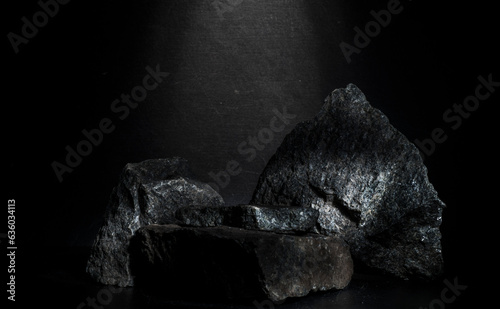 black stones for podium.black natural stones with texture for product presentation podium background. minimalistic composition with stones on a dark gray background with a light accent for the podium.