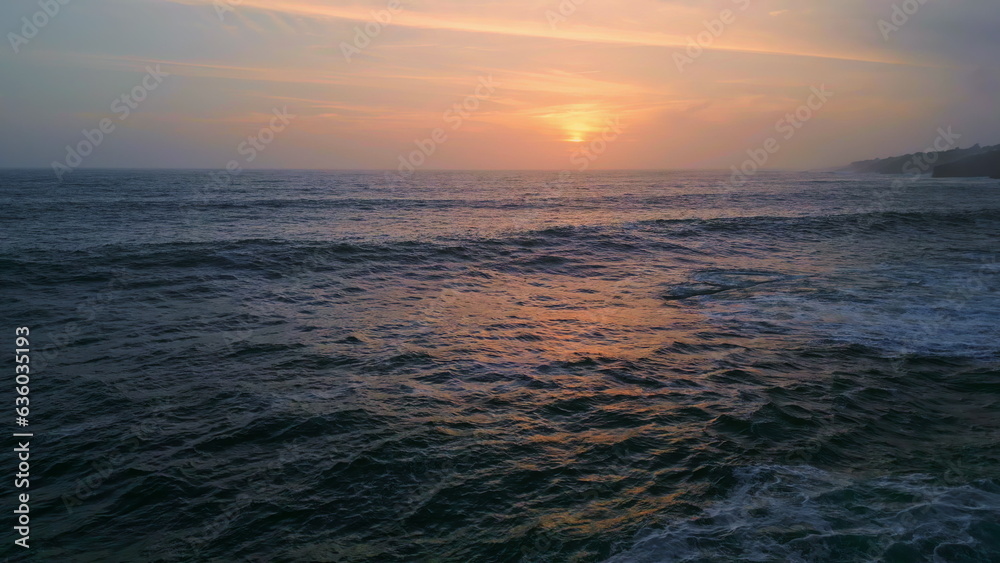 Dramatic evening marine horizon with golden sunset light at cloudy sky aerial.