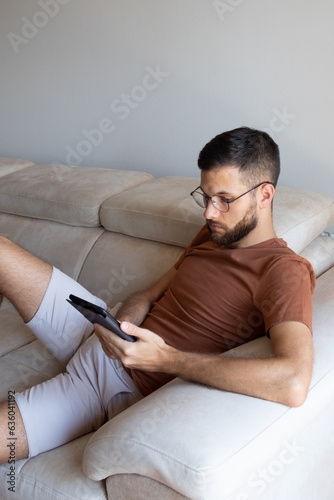 Young male model reading kindle and lounging on the sofa  photo