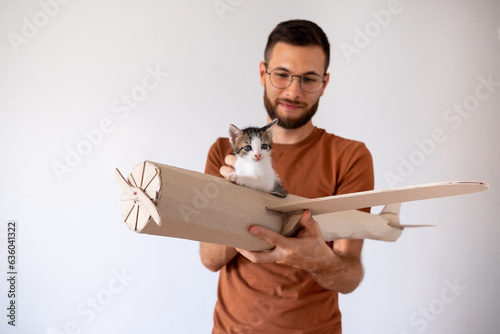 Young male model playing with the kitten in handmade toy airoplane. photo
