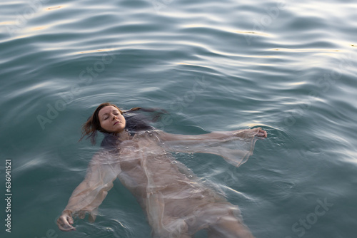 mindfulness, woman floating in water with closed eyes in nature photo