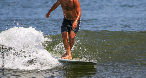 Man surfing with his legs crossed while walking up his board