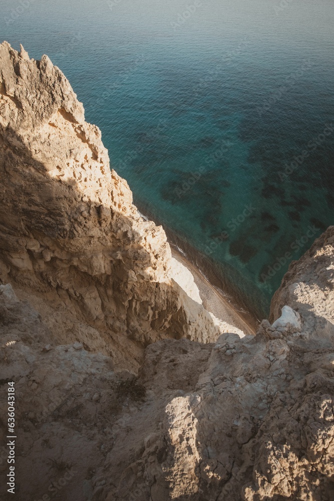 Vertical shot of rocky cliffs over the water near Pissouri trail, Cape Aspro, Pissouri, Cyprus Vertical shot of rocky cliffs over the water near Pissouri trail, Cape Aspro, Pissouri, Cyprus