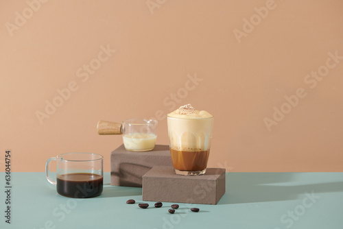 Coffee drink with milk, ice and whipped foam on a brown background 