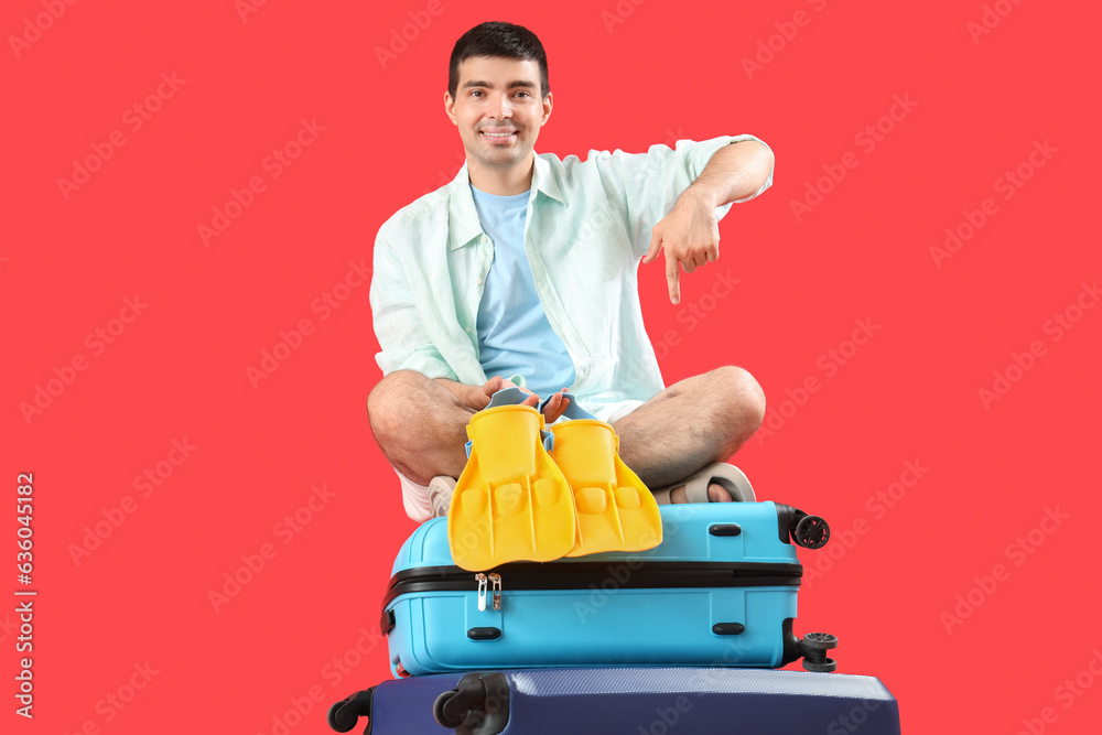Male tourist with suitcases and paddles on red background Male tourist with suitcases and paddles on red background