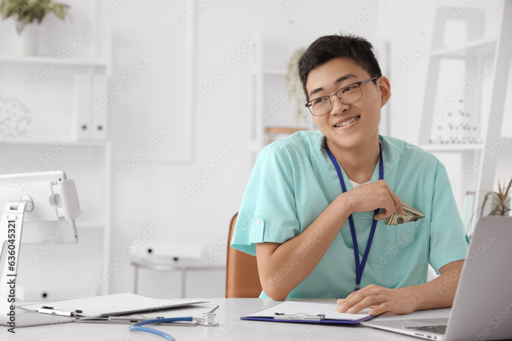 Male Asian doctor with bribe in clinic Male Asian doctor with bribe in clinic