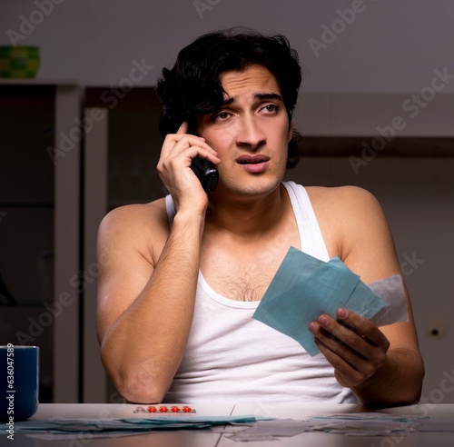 Young man calculating expences night at home photo