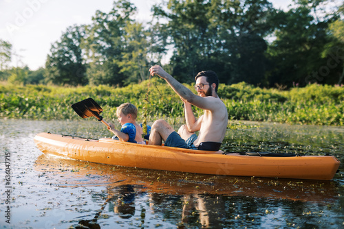 father and son kayaking together in a kayak on a river photo