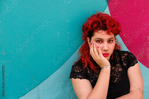 Non-binary person posing in front of colorful wall