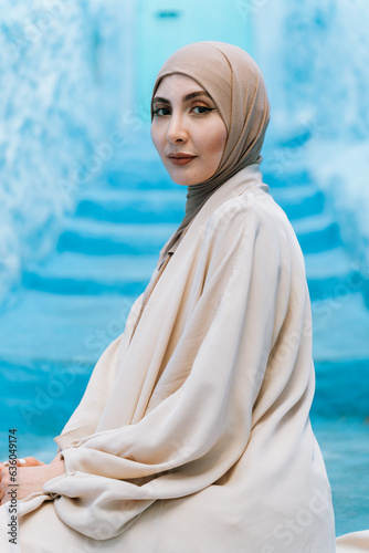 Muslim woman with a strong gaze, posing over blue background  photo