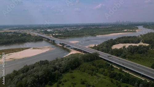 Anna Jagiellon Bridge, Warsaw over the Vistula River. A small amount of water in the river. Water shortage, sandy island close to bridge. Houses in the forest. Many cars over the bridge. 4K 59.94 fps photo