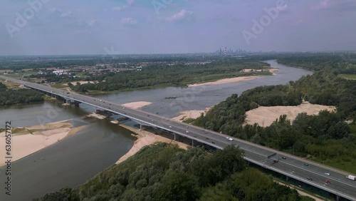 Anna Jagiellon Bridge, Warsaw over the Vistula River. A small amount of water in the river. Water shortage, sandy island close to bridge. Houses in the forest. Many cars over the bridge. 4K 59.94 fps photo