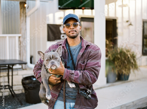 An African American man holding a french bulldog photo