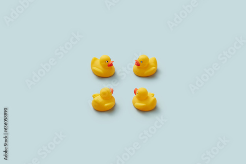 Four yellow rubber duckies on plain background.