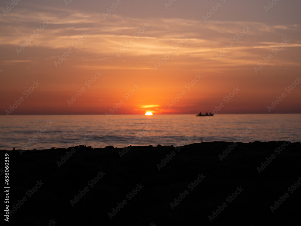 Sunset in Italy Toskana at mittelmeer with fishing boat in the water and small Waves Sunset in Italy Toskana at mittelmeer with fishing boat in the water and small Waves