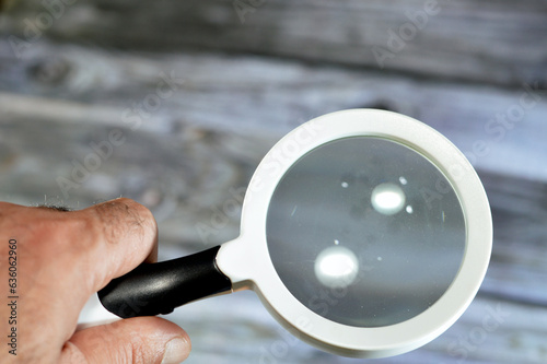 A magnifying glass, a convex lens that is used to produce a magnified image of an object, The lens is mounted in a frame with a handle, an icon of detective fiction, can be used to focus light