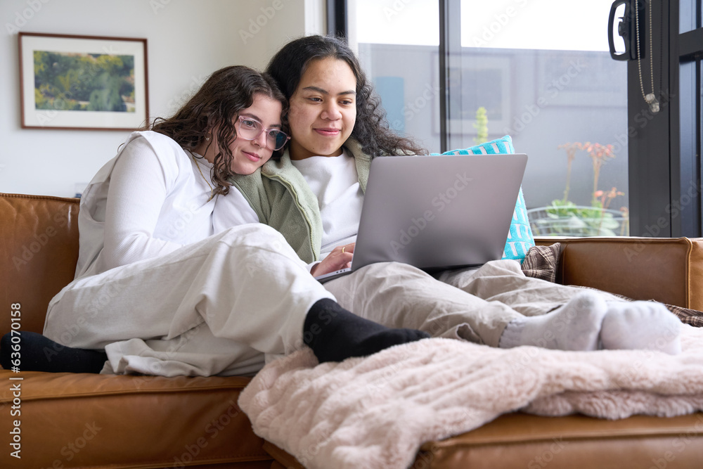 Young lesbian couple cuddle up and watch movie together on laptop Young lesbian couple cuddle up and watch movie together on laptop