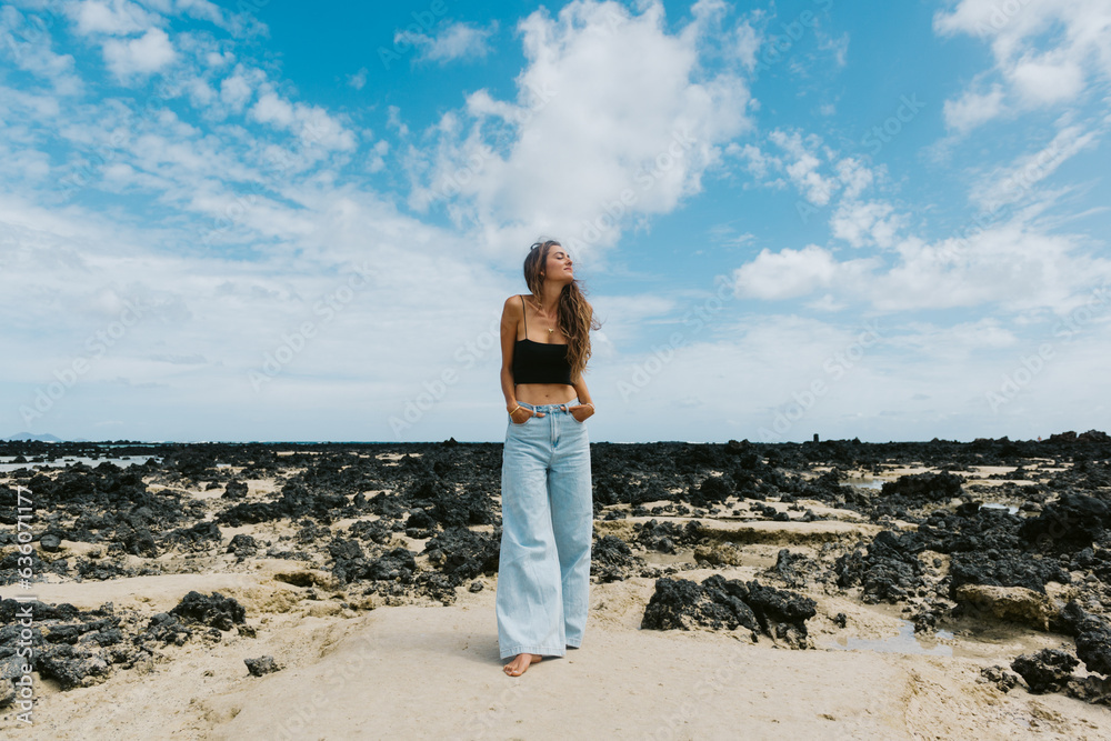 woman on a black rock beach dressed in jeans woman on a black rock beach dressed in jeans