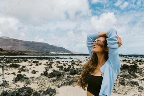 woman on a black rock beach dressed in jeans photo