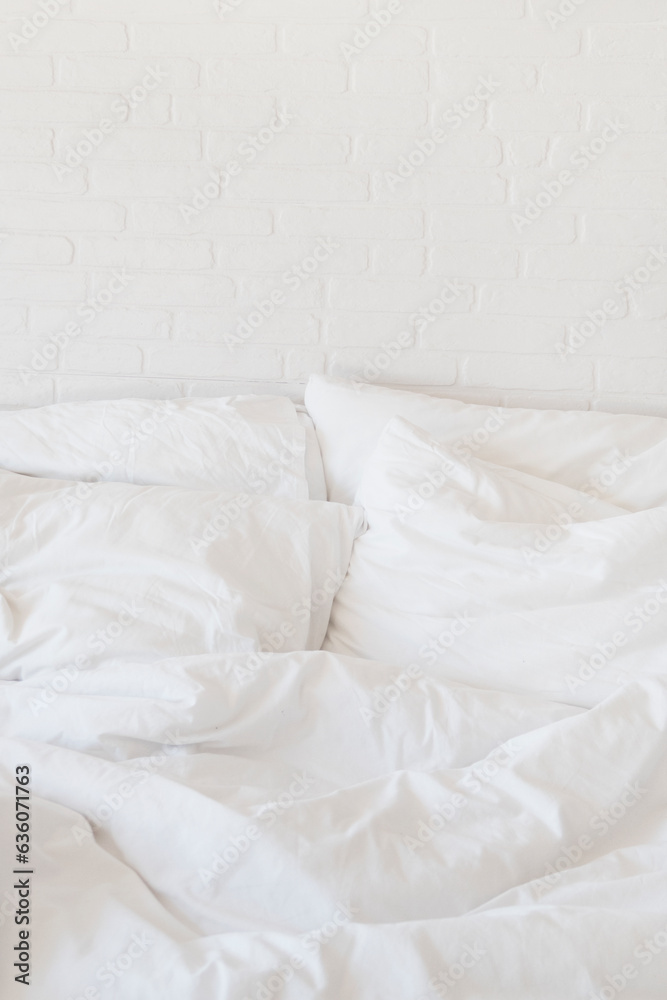 white bed sheets and pillows and white brick wall white bed sheets and pillows and white brick wall