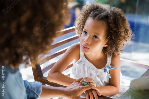 Little girl having a serious talk with her mother sitting on chair photo