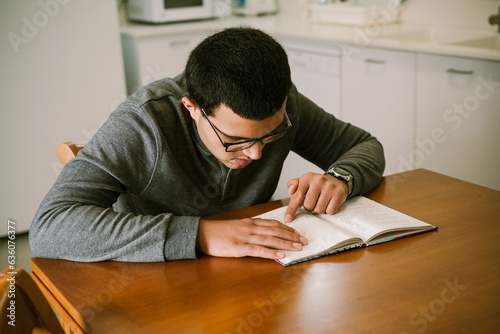 Young Teen Reading Book at Home. photo
