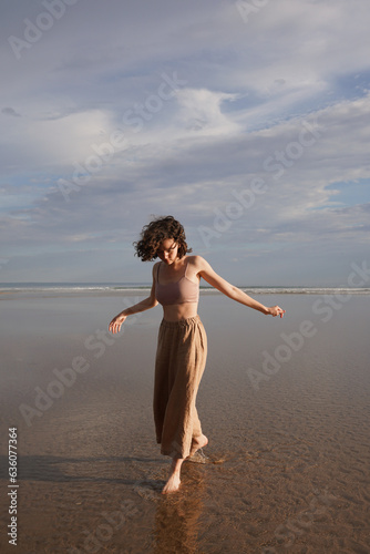 A young curly-haired girl walks by the Atlantic ocean