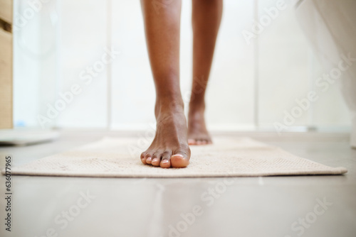 Barefoot woman getting out of the shower photo