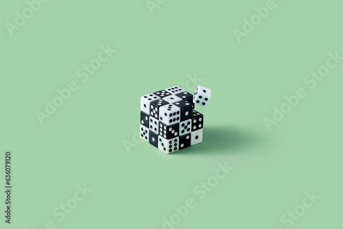 Cube made of black and white dice against green background.