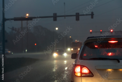 Cars driving at rainy night at traffic lights on american wide road intersection in city area. Transportation system in USA