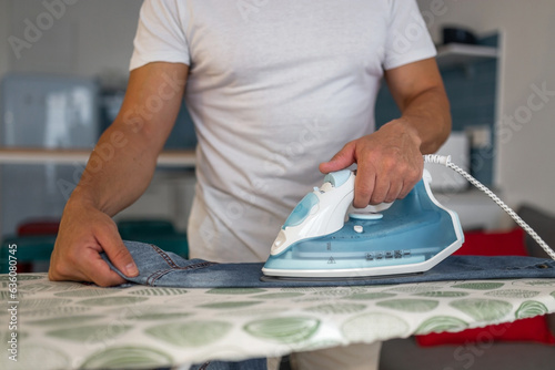 young man ironing clothes at home photo