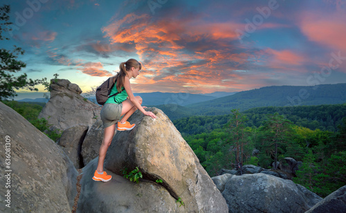 Hiker woman clambering on rocky mountain footpath in evening nature. Lonely female traveler traversing hard wilderness trail. Healthy lifestyle and sport concept