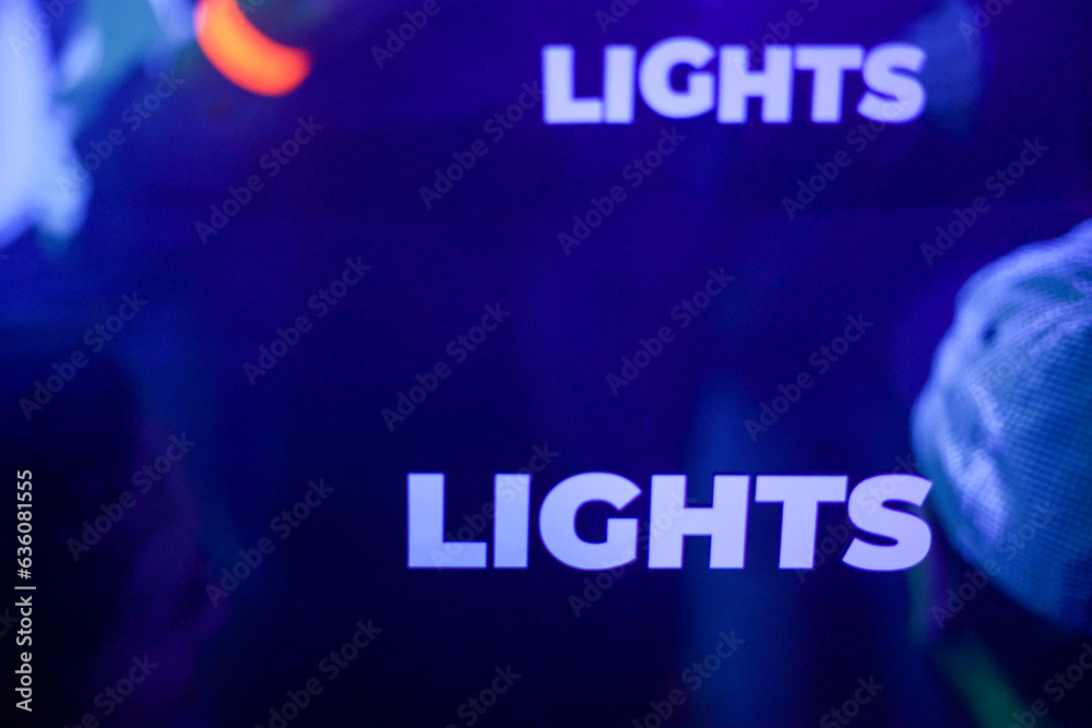 Projection of the word lights at party next to anonymous man in in hat Projection of the word lights at party next to anonymous man in in hat