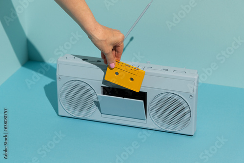 Woman inserting cassette into colorful boombox. Music concept. photo