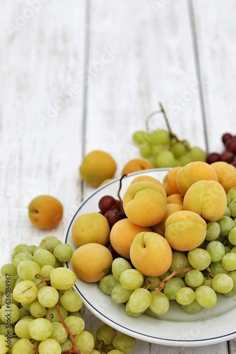 Apricots and grapes  on a white wooden table  free space  place for text  background image for presentations  background  summer