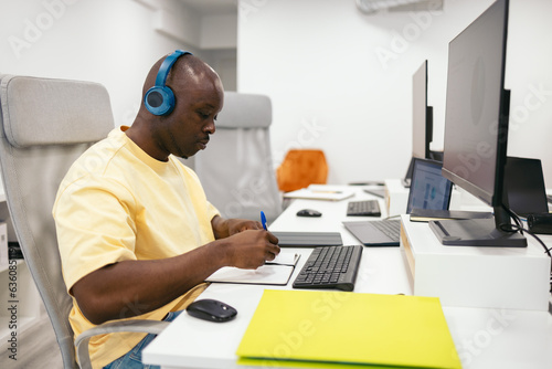 Concentrated black man working in the office with headphones photo