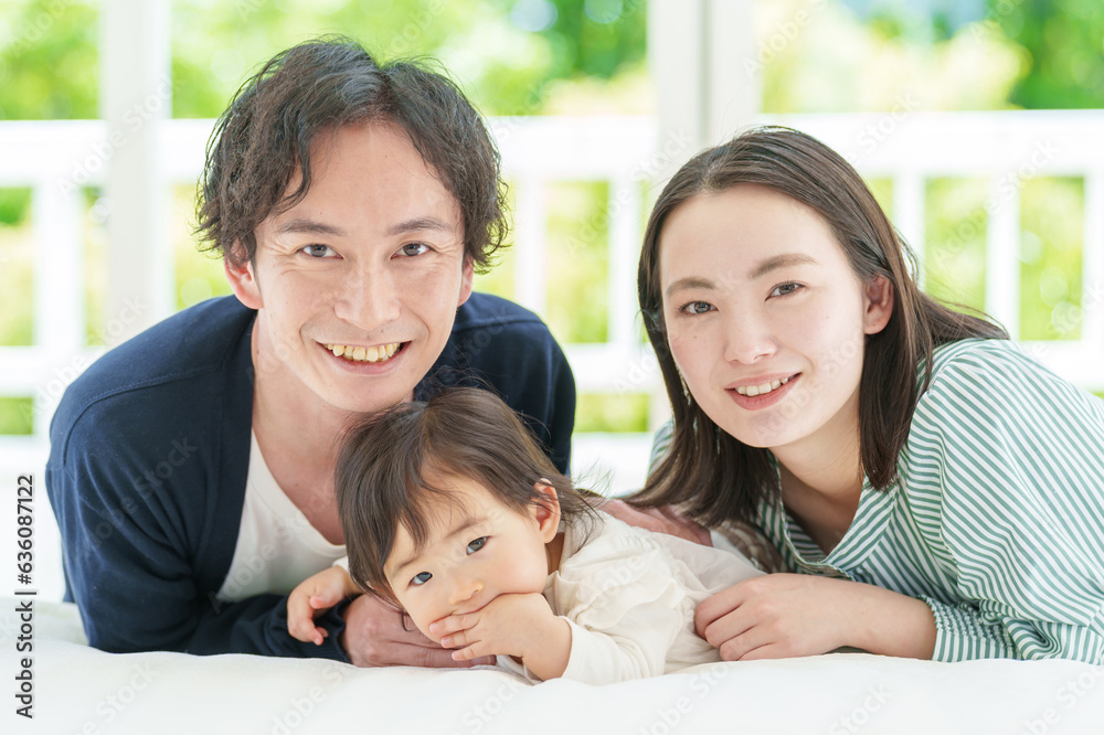 ベッドでリラックスする夫婦と赤ちゃんのポートレート