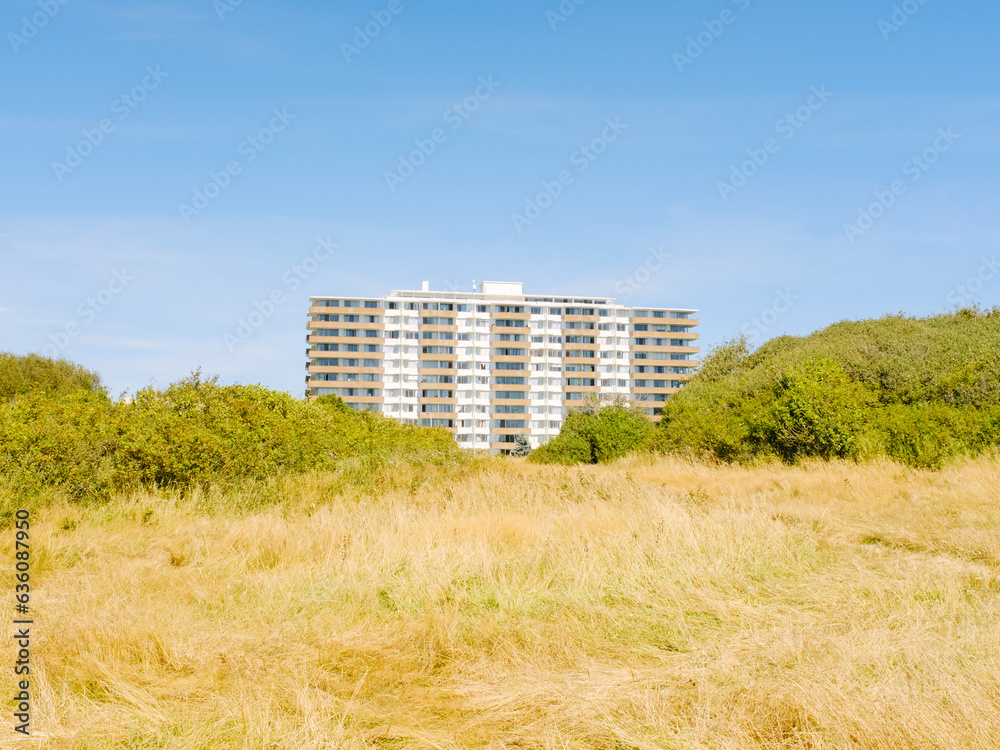 Green hillside obscuring large condo in distance Green hillside obscuring large condo in distance