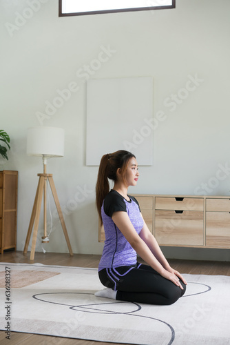 Young asian woman doing yoga exercise vajrasana diamond pose for workout healthy lifestyle at home photo