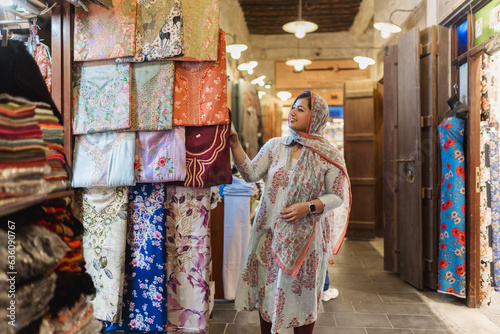 Muslim female buyer choosing wear at market photo