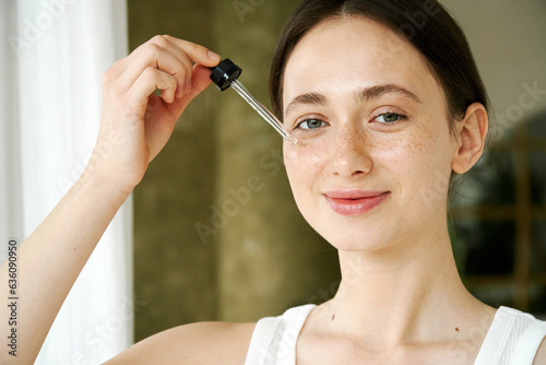 Happy Woman Applying Facial Serum With Dropper Moisturizing