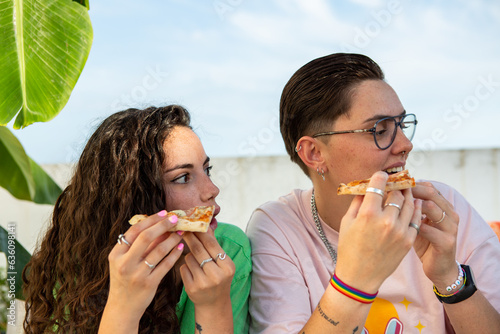 Two people holding pizza look to the side photo